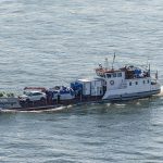 Small ferry transporting a vehicle across the water